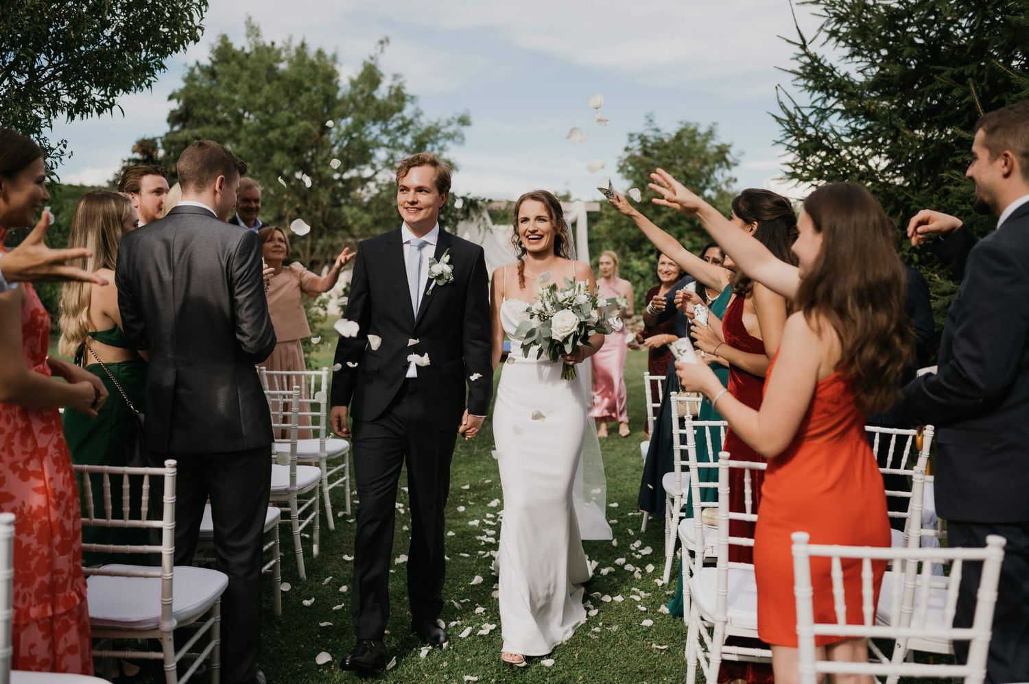 Wedding guests shower the newlyweds with confetti during their outdoor ceremony recessional.
