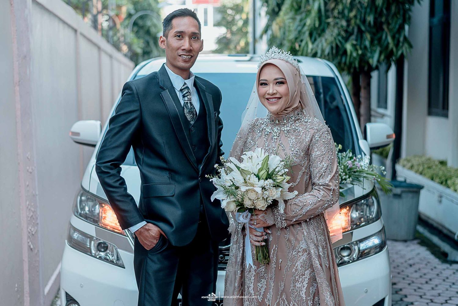 Wedding couple standing beside a white car during their celebration photoshoot.