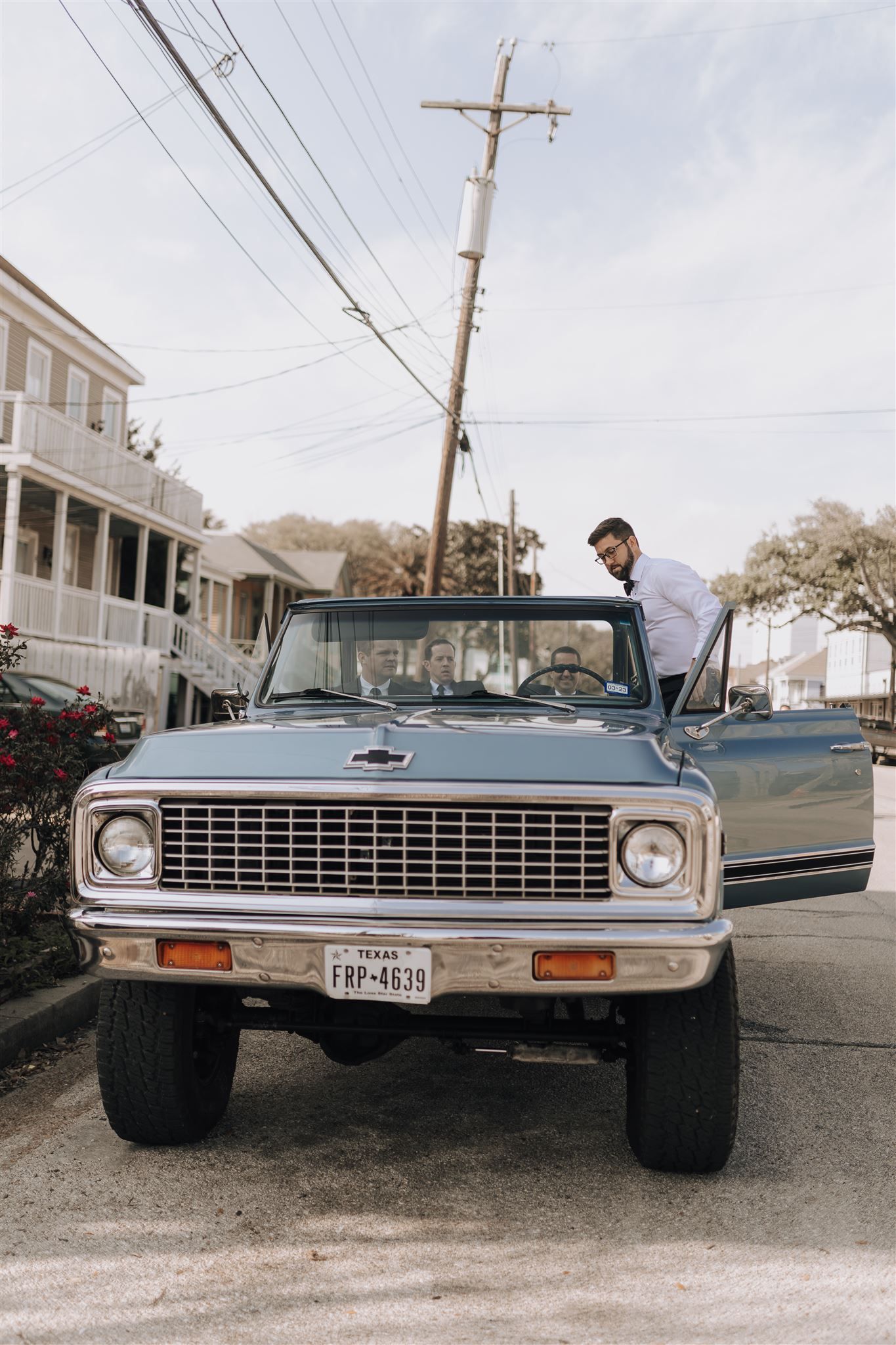 A classic Chevrolet pickup truck parked on a residential street with power lines overhead.