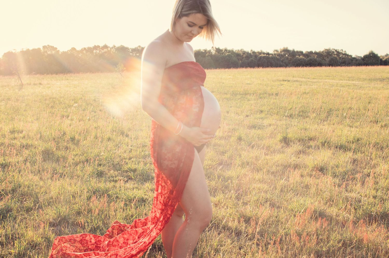 pregnant woman embracing belly in red dress