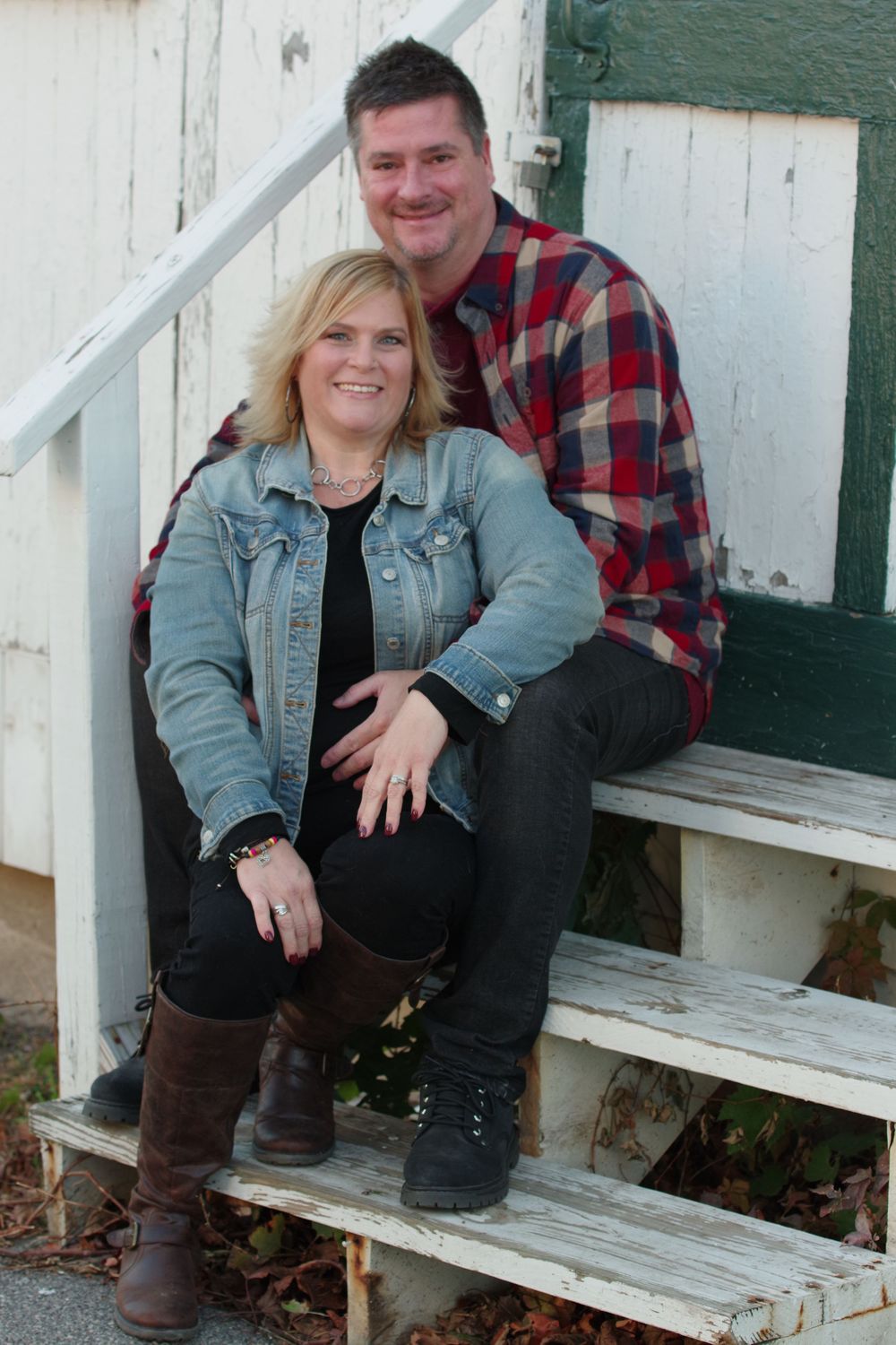 A couple poses on white wooden stairs wearing coordinating casual outfits.