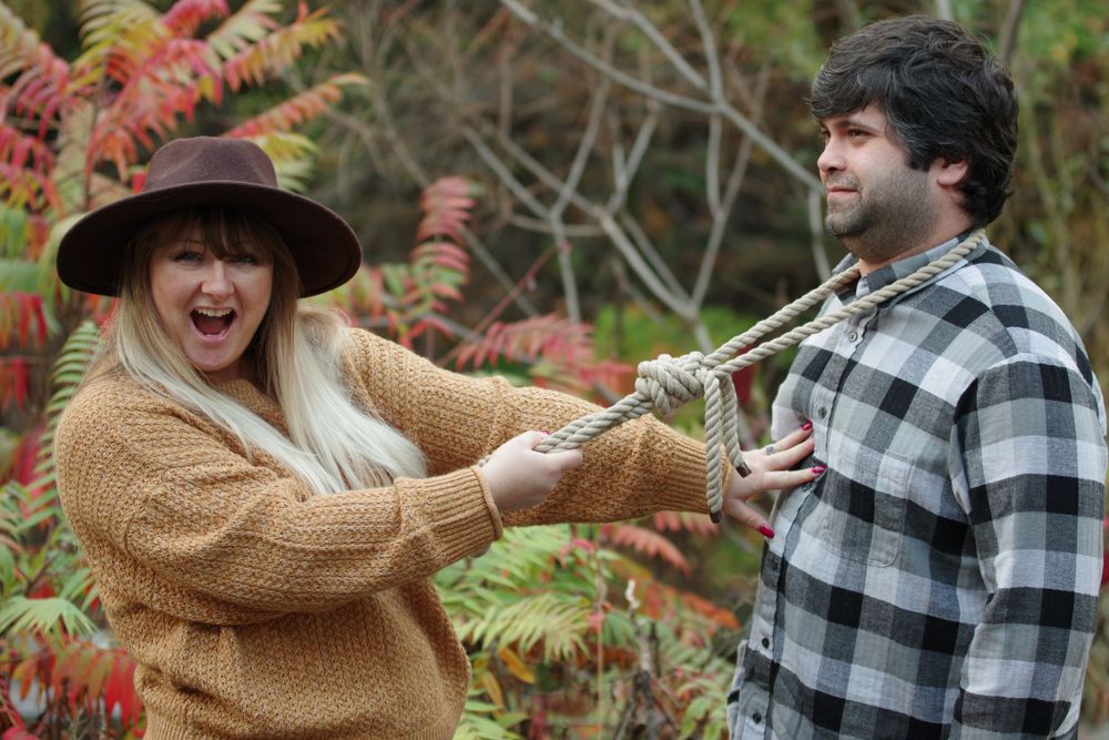 A playful autumn photoshoot moment captured with colorful fall foliage in the background.