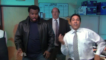 Two people dancing and celebrating in an office setting.