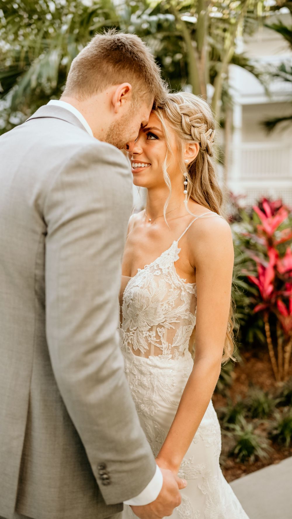 Intimate moment between wedding couple against tropical garden background.