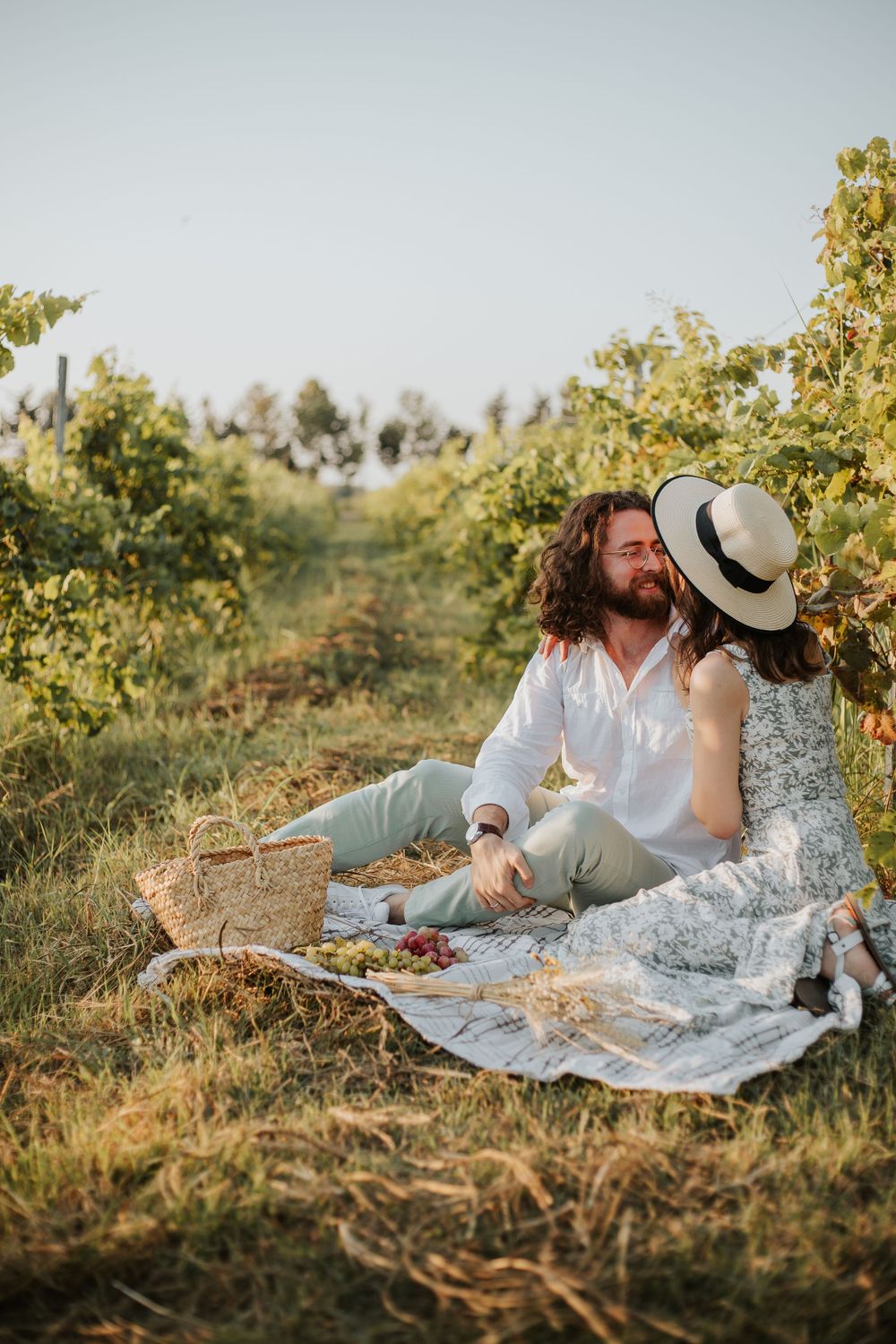 A couple shares an intimate moment during their vineyard picnic.