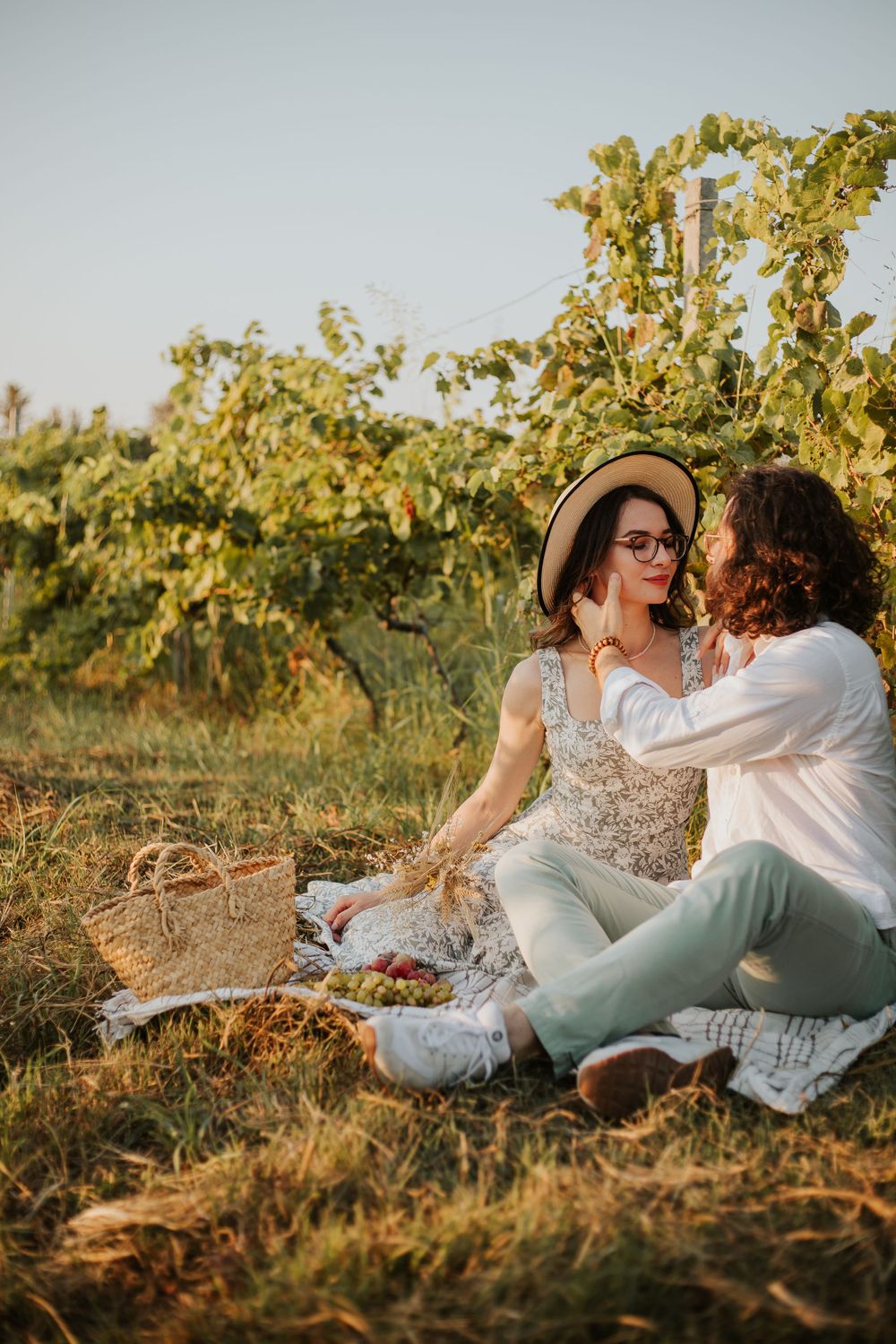 A romantic picnic scene in a sunny vineyard with a couple sharing an intimate moment.