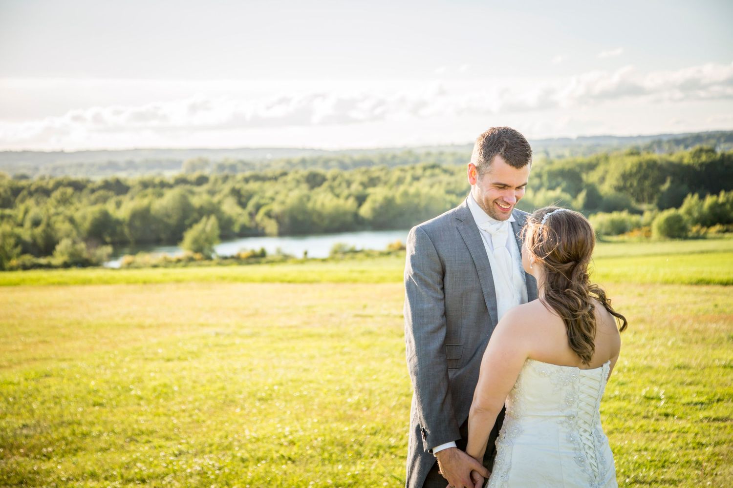 A couple sharing an intimate moment at sunset in a golden meadow with rolling hills in the background.