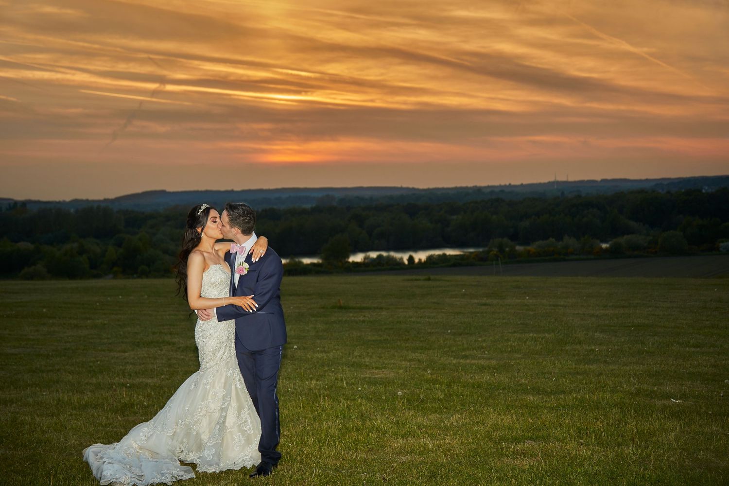 A romantic sunset wedding portrait in a sweeping countryside landscape.