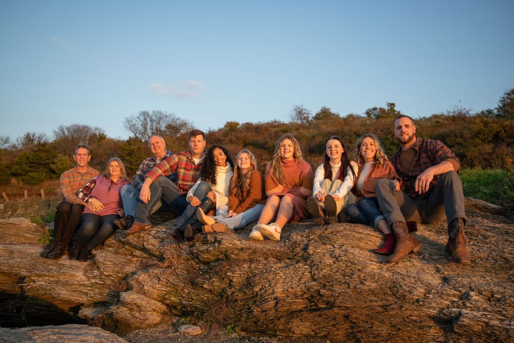 Group photo session on rocky coastal terrain during golden hour.