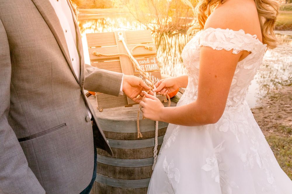 Close-up of couple exchanging rings during rustic outdoor wedding ceremony.