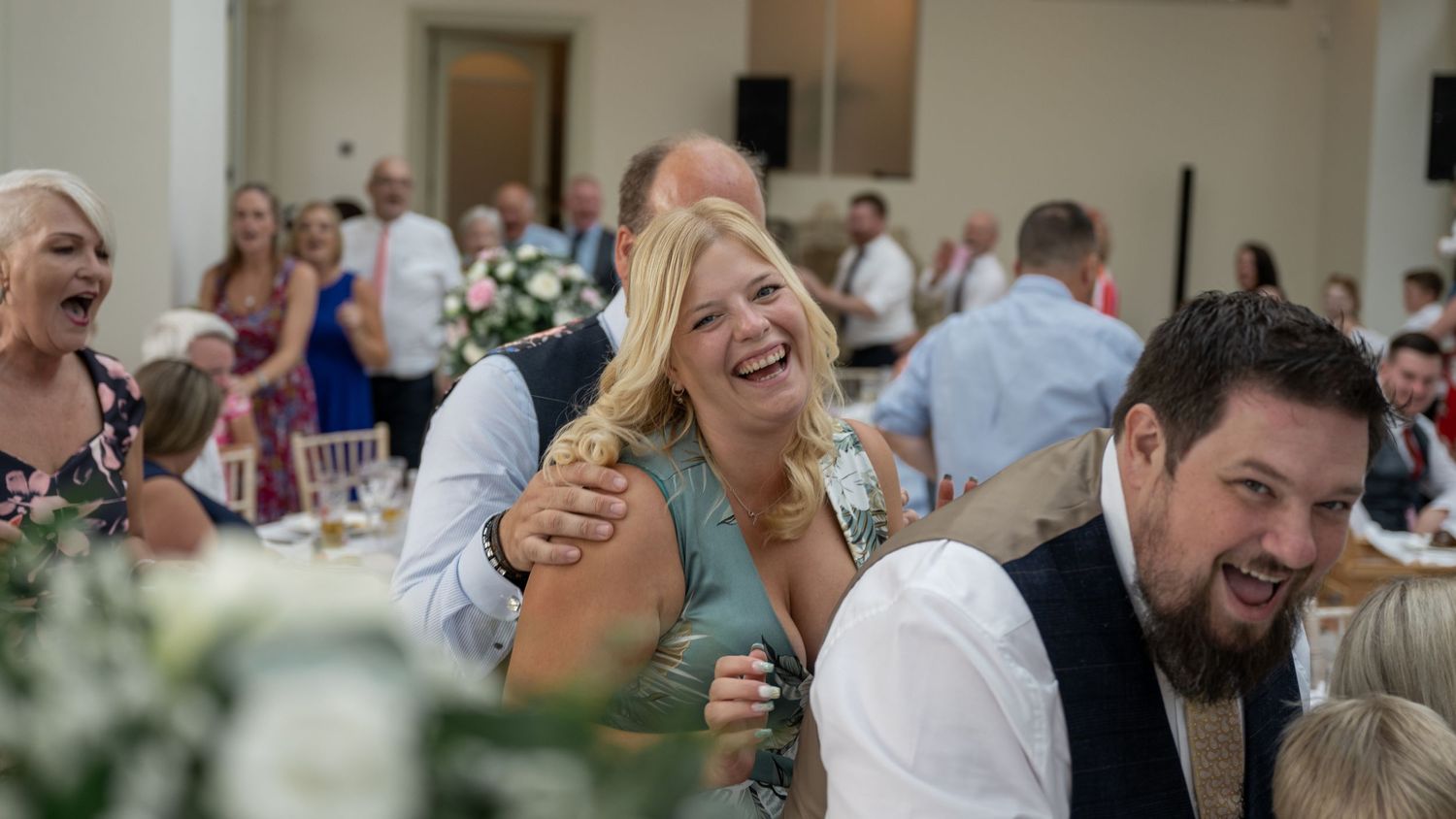 Joyful wedding reception celebration with guests laughing and enjoying festivities.
