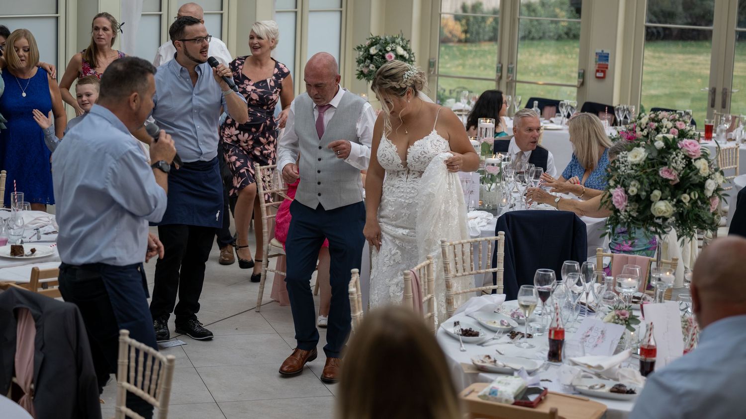Wedding guests enjoying entertainment and dancing during reception in elegant venue.