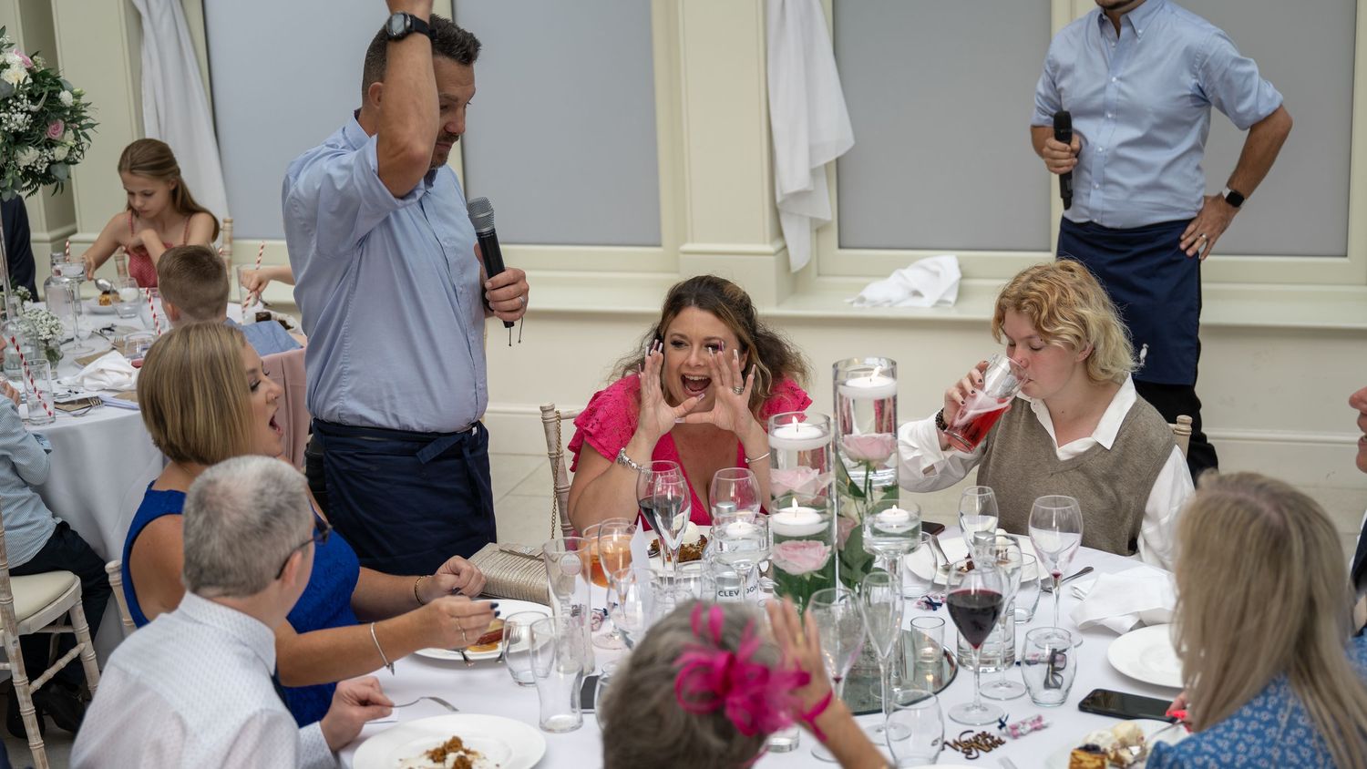Guests gathered around elegant table during wedding reception with paper airplanes and festive decorations.