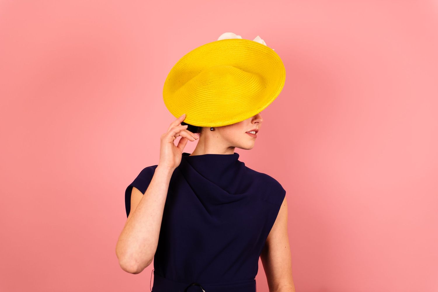 Model in a Navy Dress and Yellow Headpiece by Lauren J Ritchie Millinery for a product shoot.