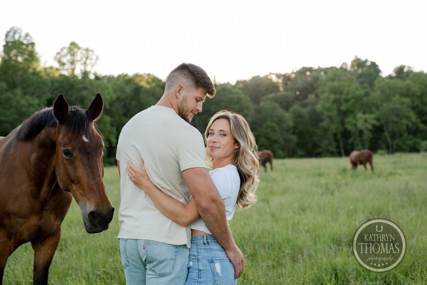 Romantic countryside photoshoot with couple and curious horse in green pasture.