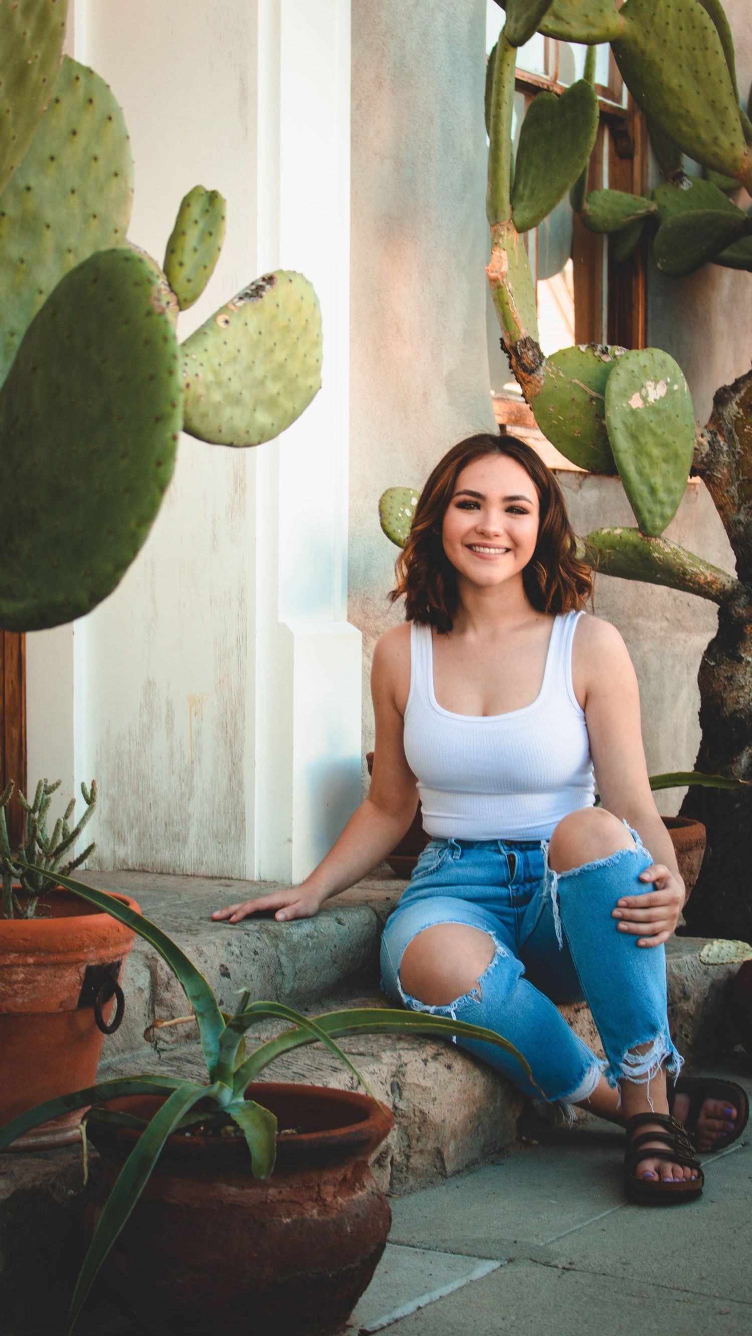 Casual portrait with potted cactus plants and southwestern architectural elements.