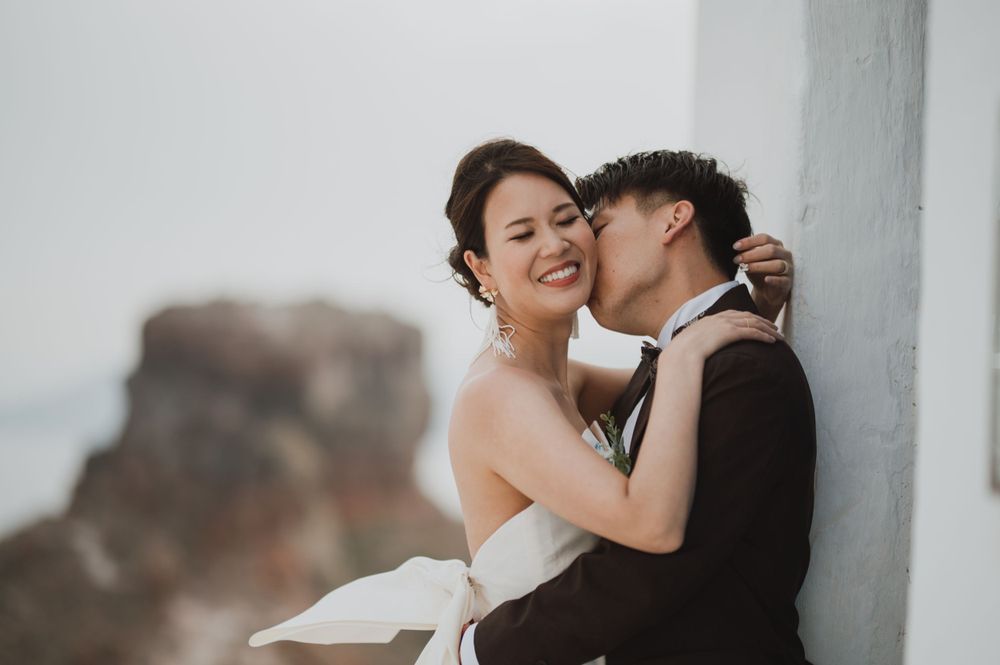Intimate wedding portrait against white Mediterranean architecture in Santorini.