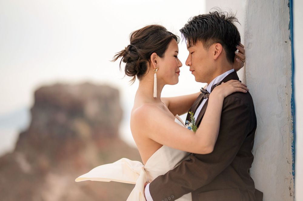A romantic wedding couple embraces against a scenic mountain backdrop during their outdoor photoshoot.