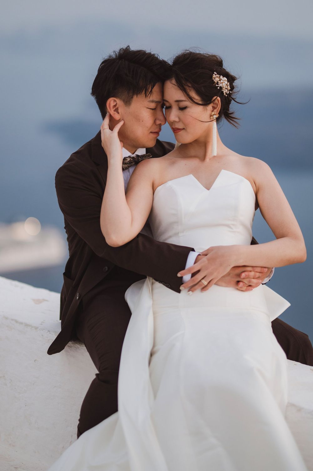 Elegant wedding portrait of couple in intimate pose against serene ocean backdrop.