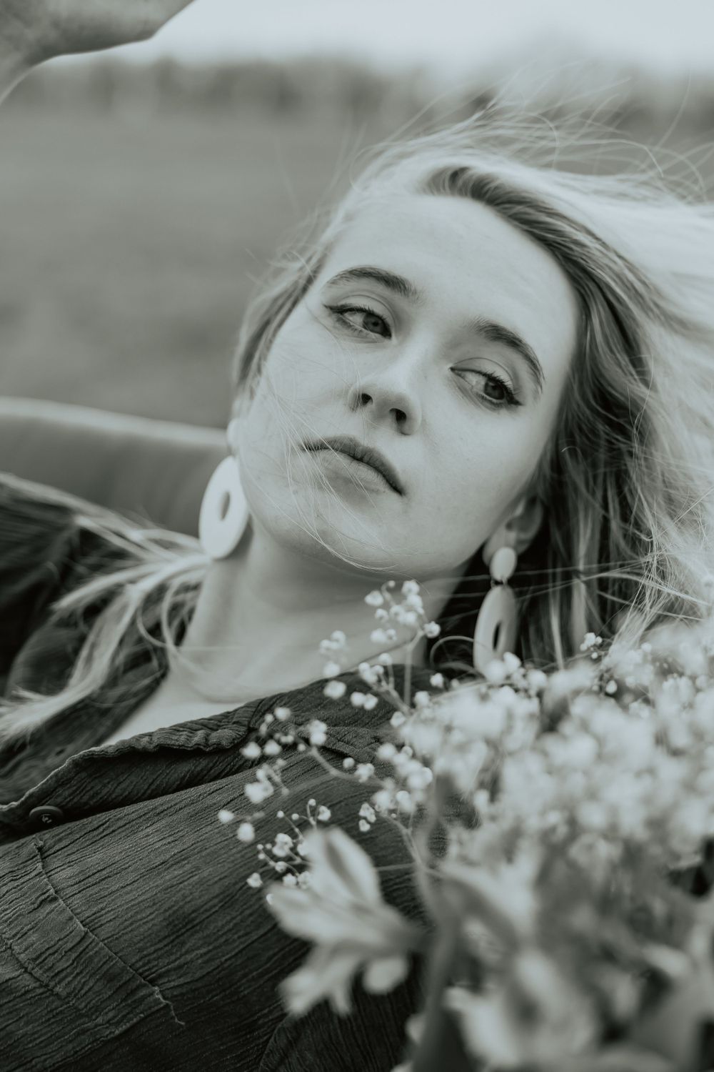 Artistic black and white portrait with delicate flowers in soft focus.
