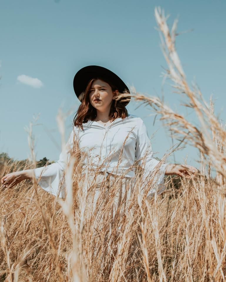 Artistic portrait series of someone in white clothing walking through golden wheat fields under blue sky.