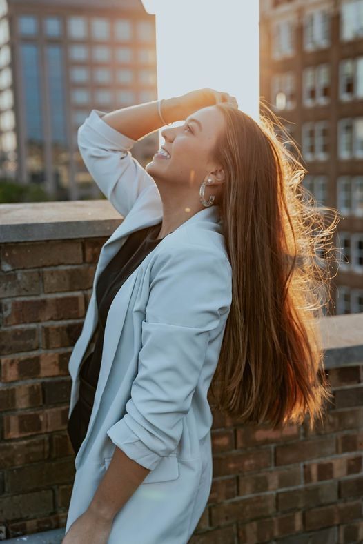 Sunset portrait against brick wall with hair flowing in natural light.