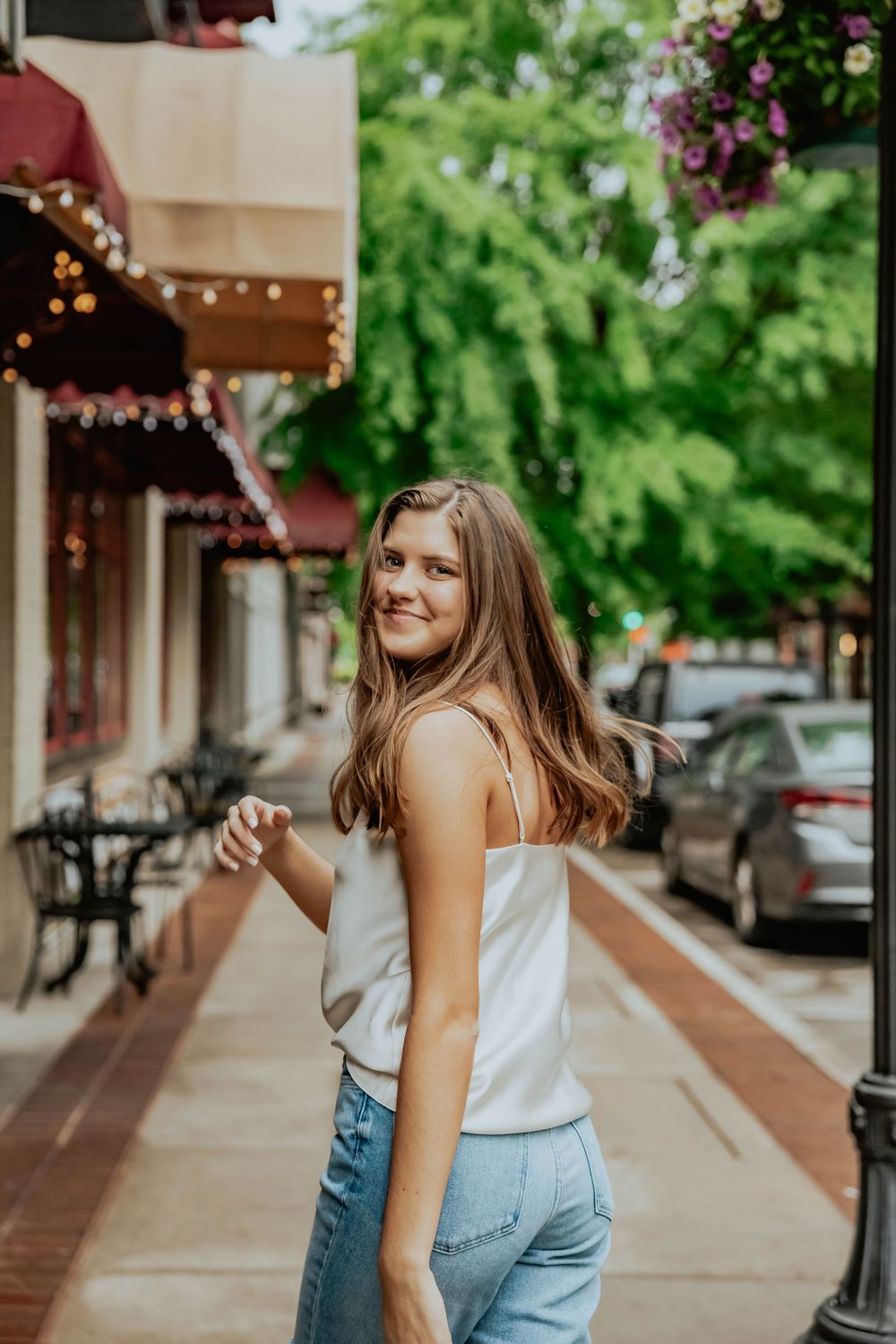 Street fashion photography with string lights and urban scenery in background.