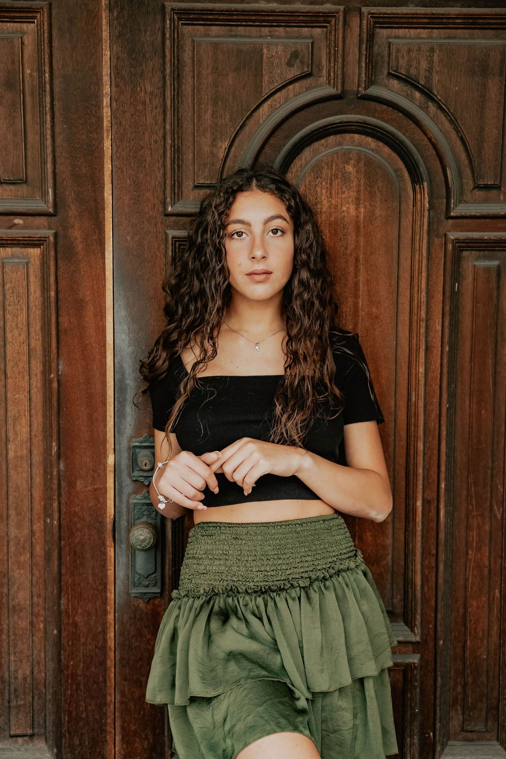 Artistic portrait series against dark wooden paneled doors with olive green clothing details.