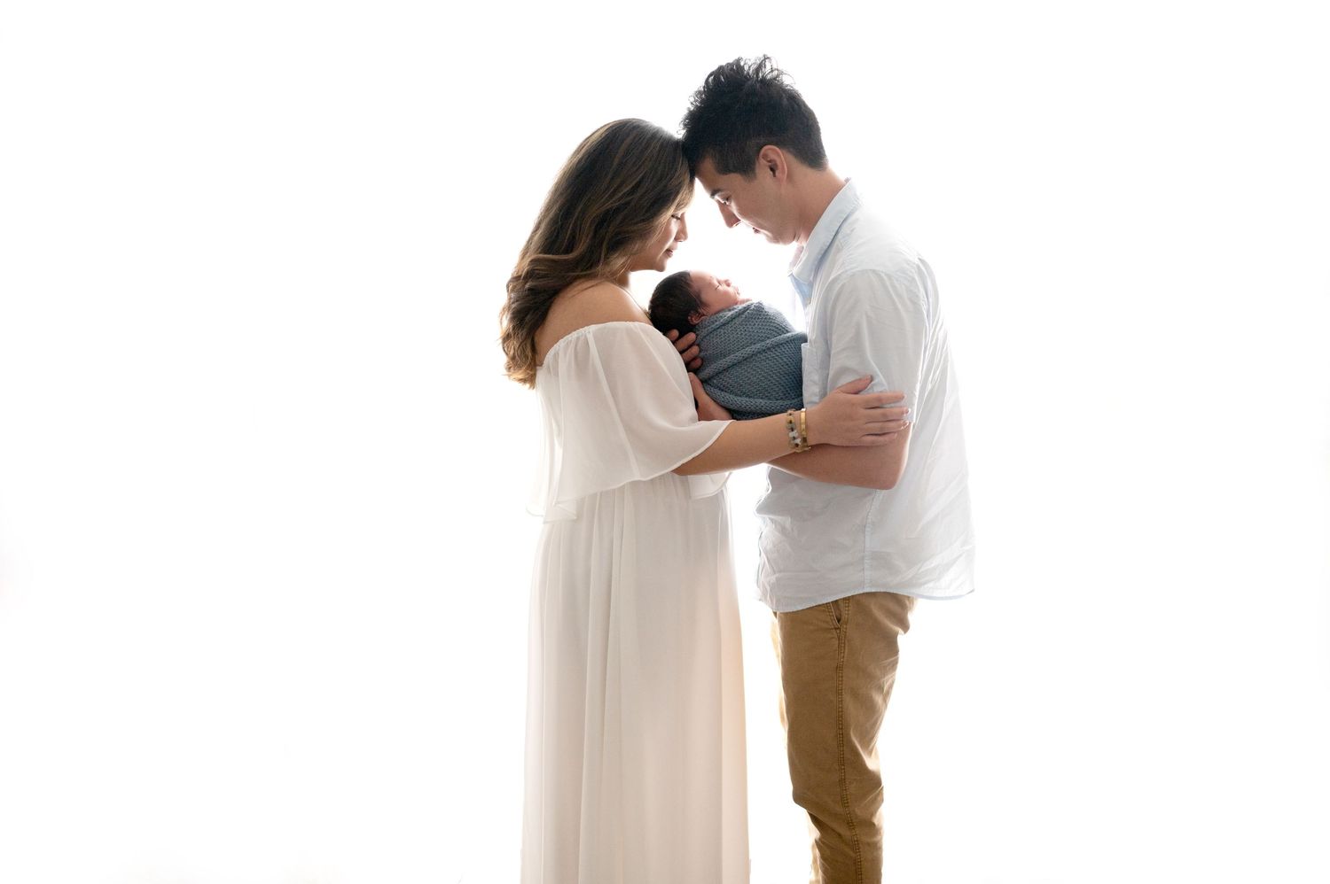Two people share an intimate moment while dressed in casual attire against white backdrop.