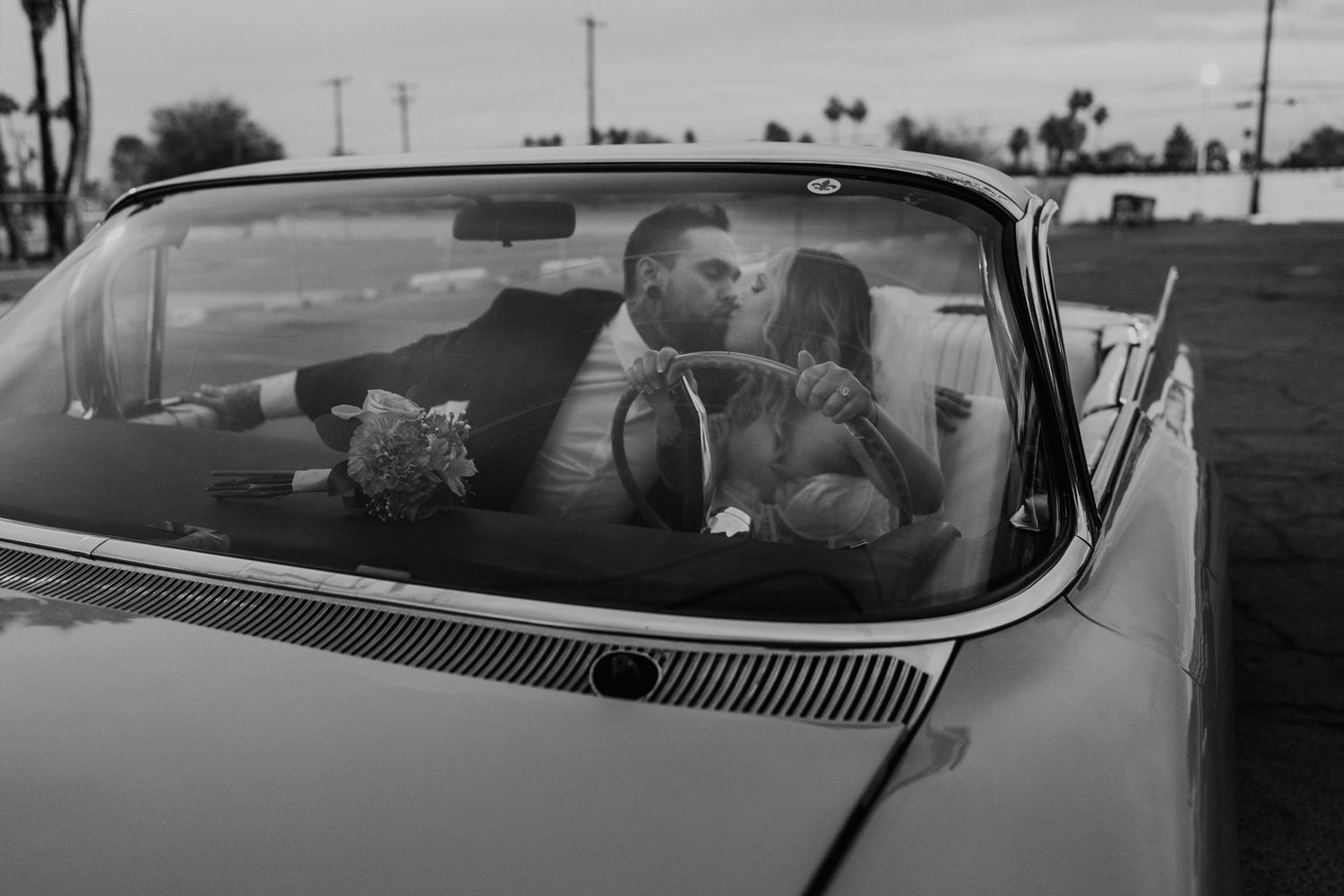 Black and white photo of couple sitting in vintage car interior.
