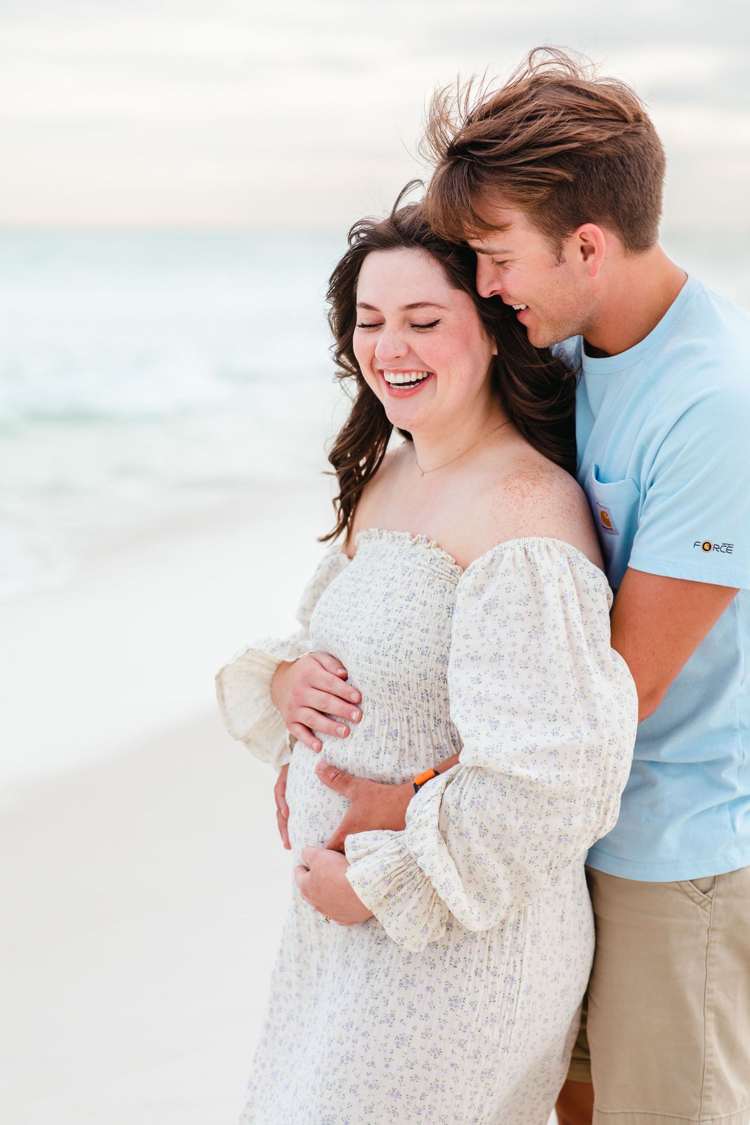 A loving embrace on the beach with soft lighting and waves in the background.