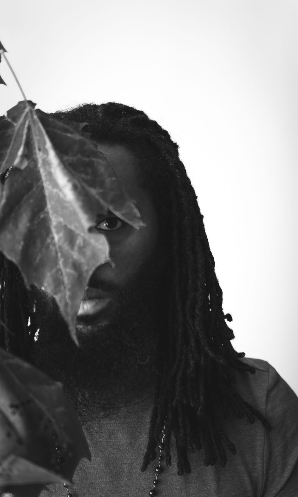 Dramatic black and white portrait partially obscured by a leaf.