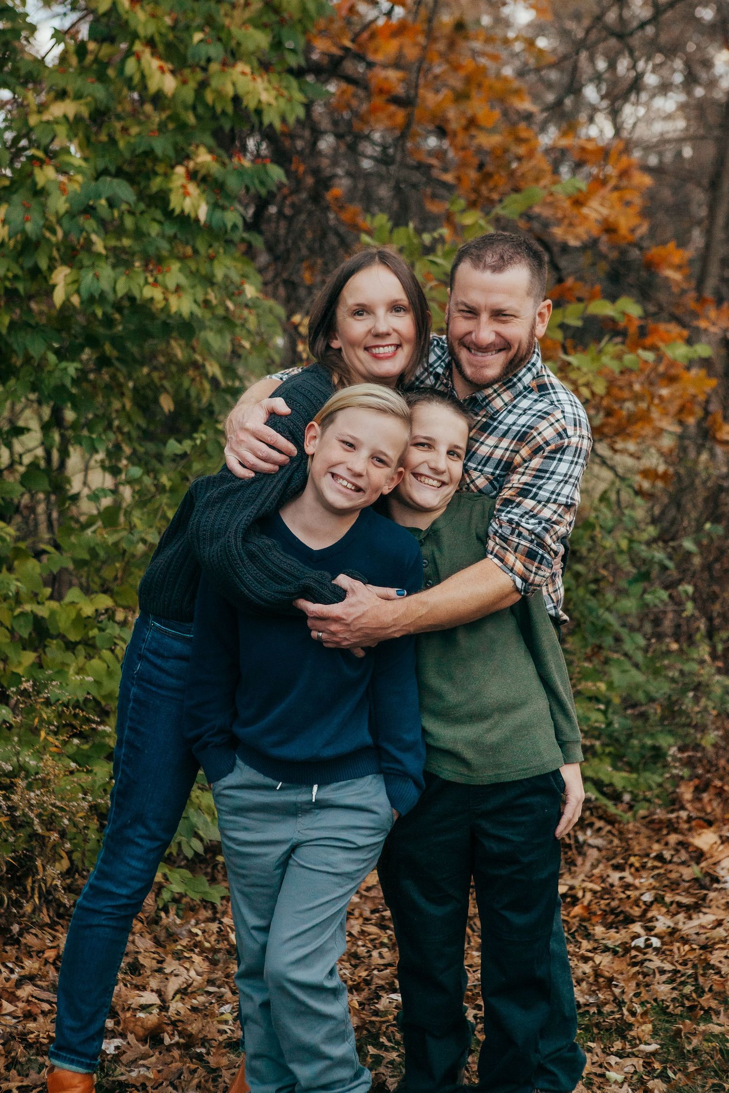 Happy family hugging and laughing together during autumn photo session.