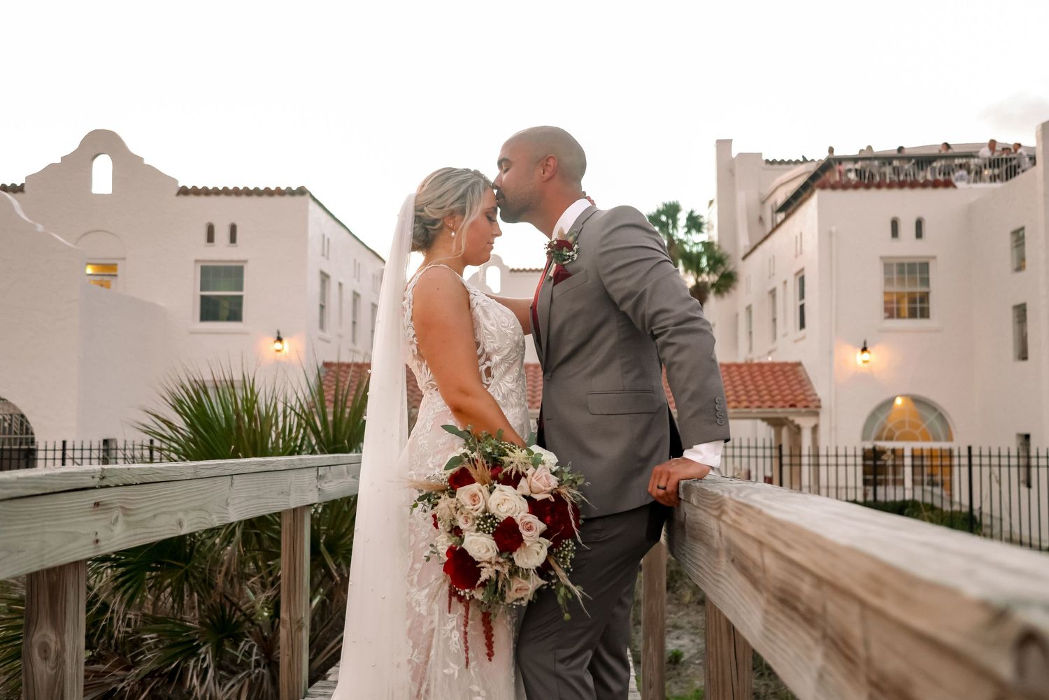 A romantic moment between newlyweds on a balcony of a Mediterranean-style building.