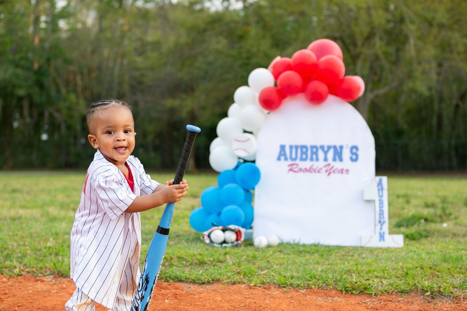 Sanford FL Cake Smash Photography baby boy smiling holding a baseball bat for his first birthday
