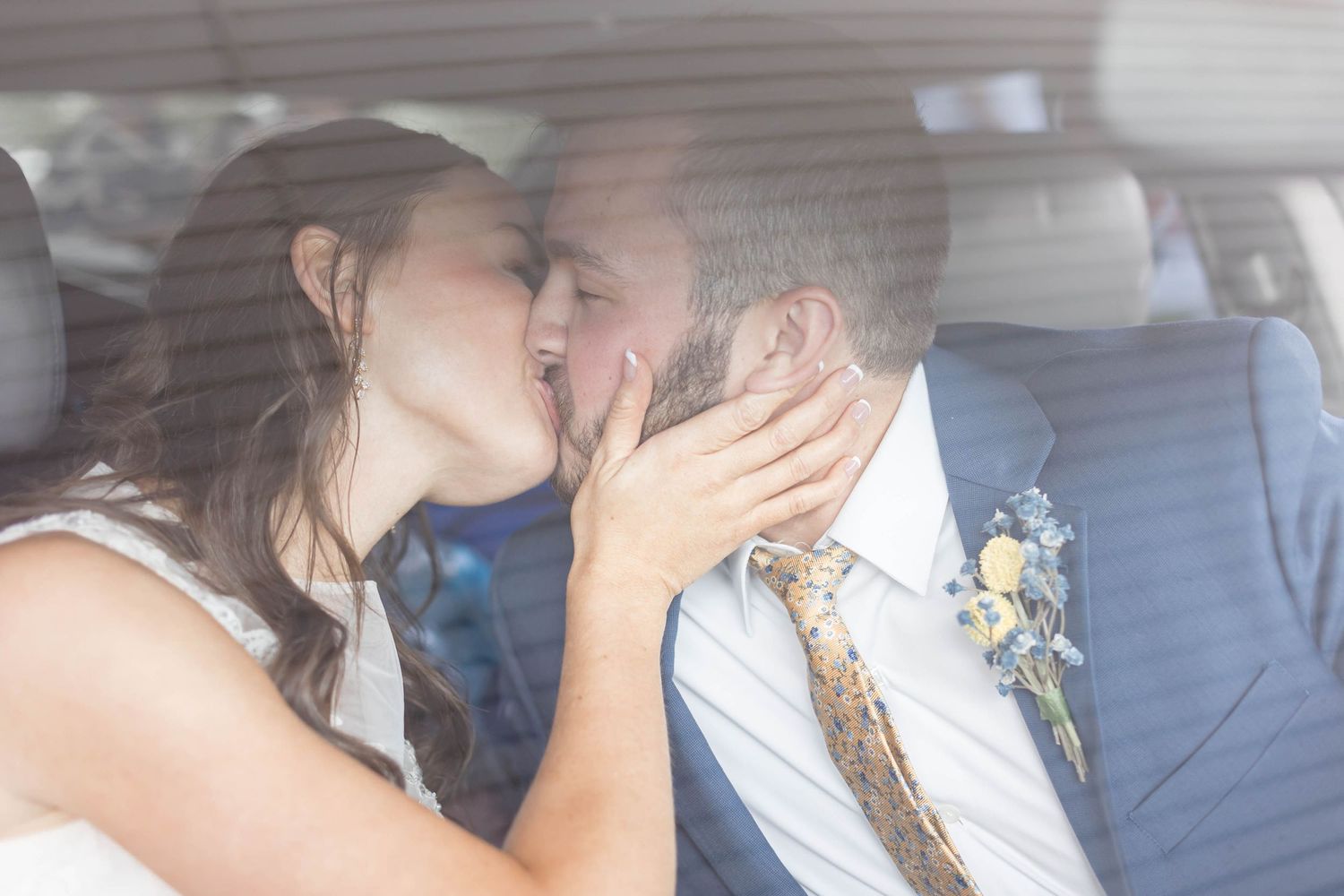 bride and groom kiss in getaway car