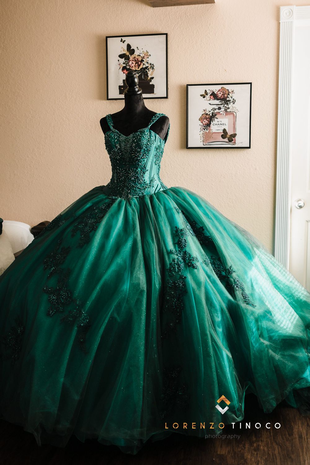 Stunning emerald green ball gown with detailed beadwork displayed on black mannequin form.