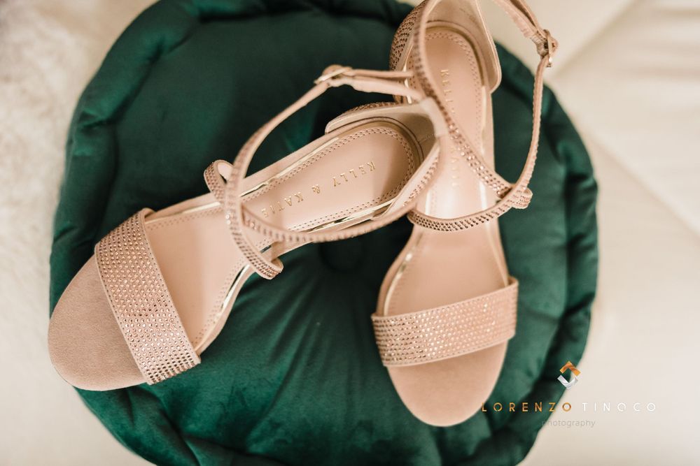 Sparkly nude strappy sandals positioned on green fabric background.