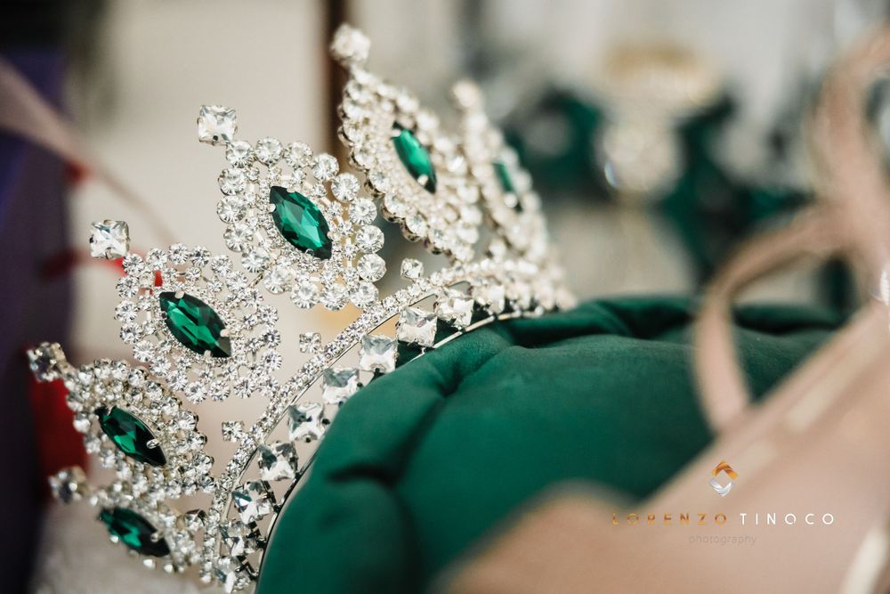 Crystal and emerald tiara crown with intricate silver detailing photographed in close-up.