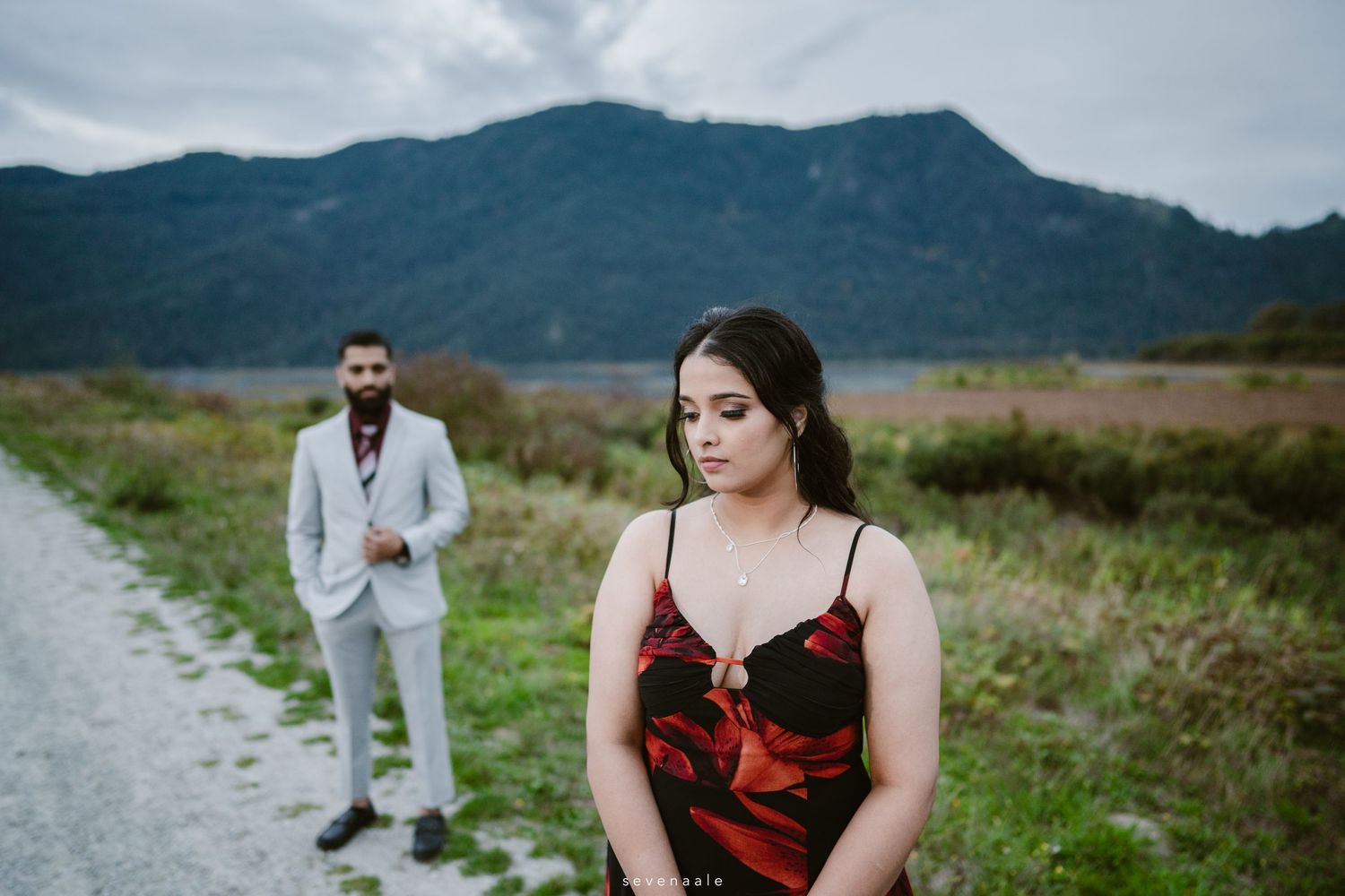 A couple in contrasting formal attire pose on a mountain path.