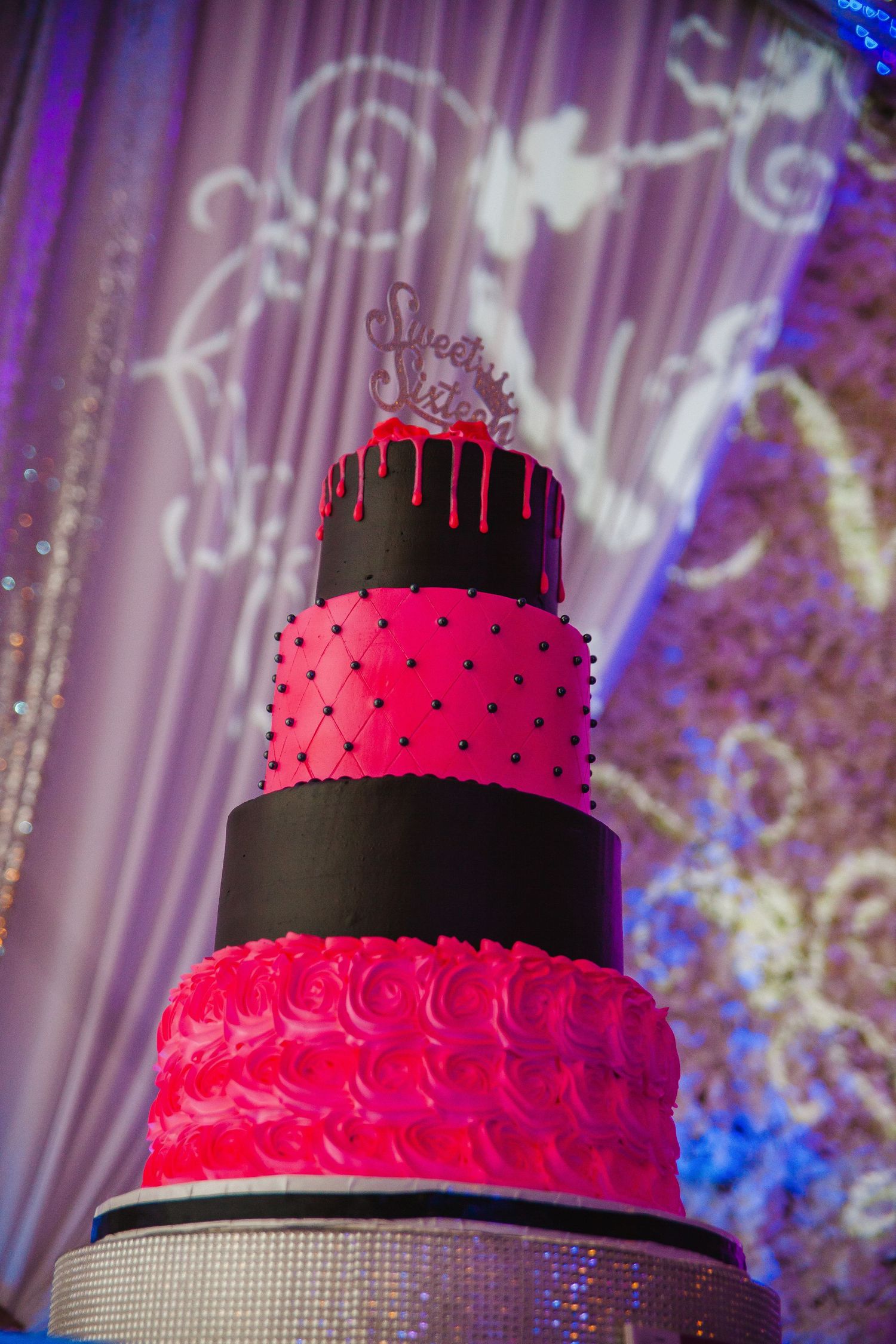 Elegant tiered black and hot pink wedding cake with detailed piping and geometric patterns.