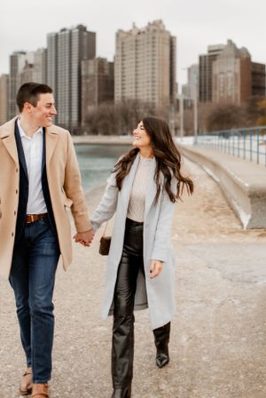 A couple takes a romantic stroll along Lake Michigan with Chicago's urban landscape behind them.
