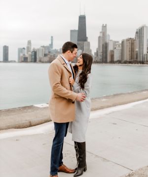 A couple shares a romantic moment along Chicago's lakefront with the iconic skyline in the background.