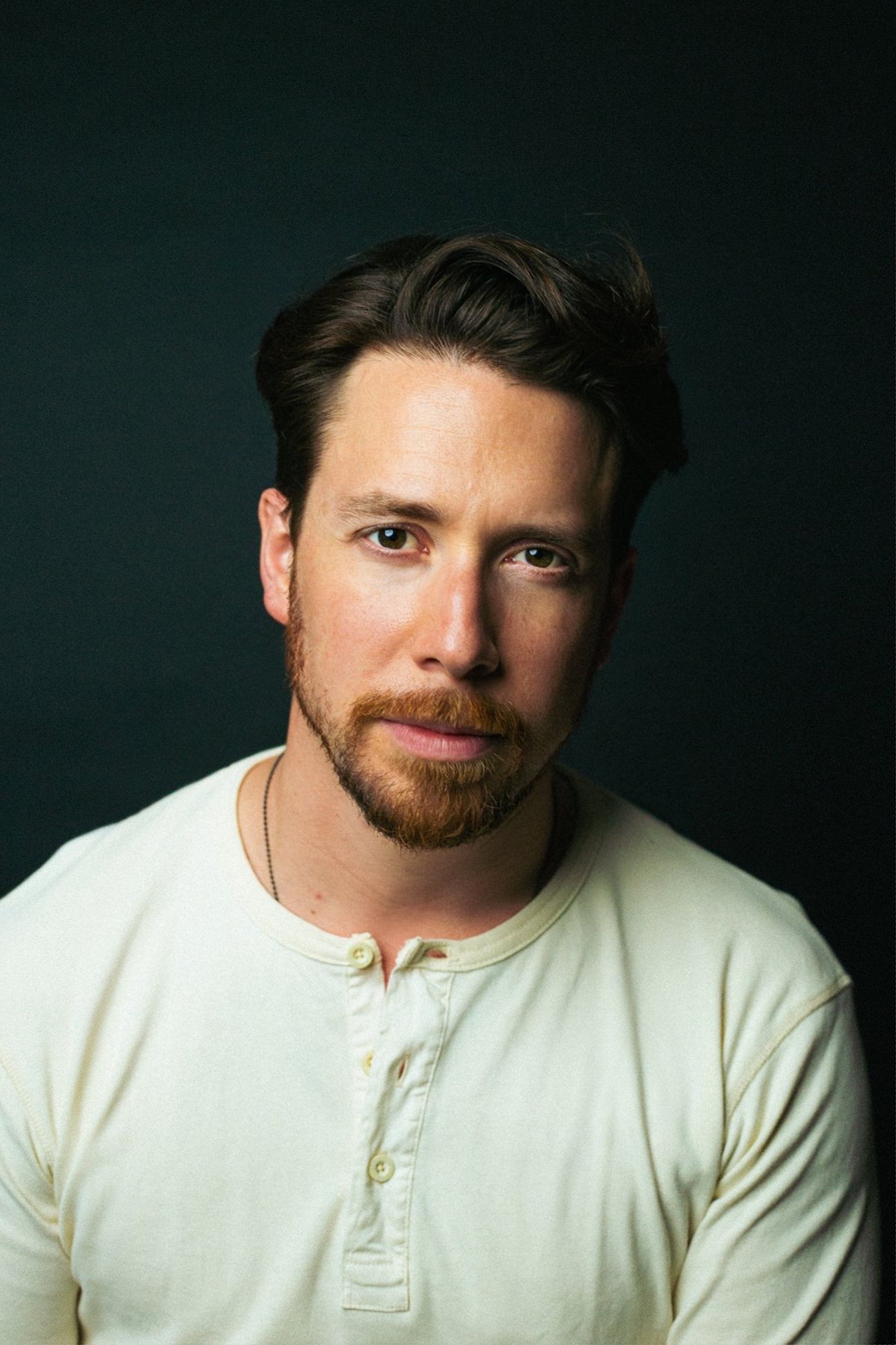 a young man with an auburn beard and hair gazes into the lens