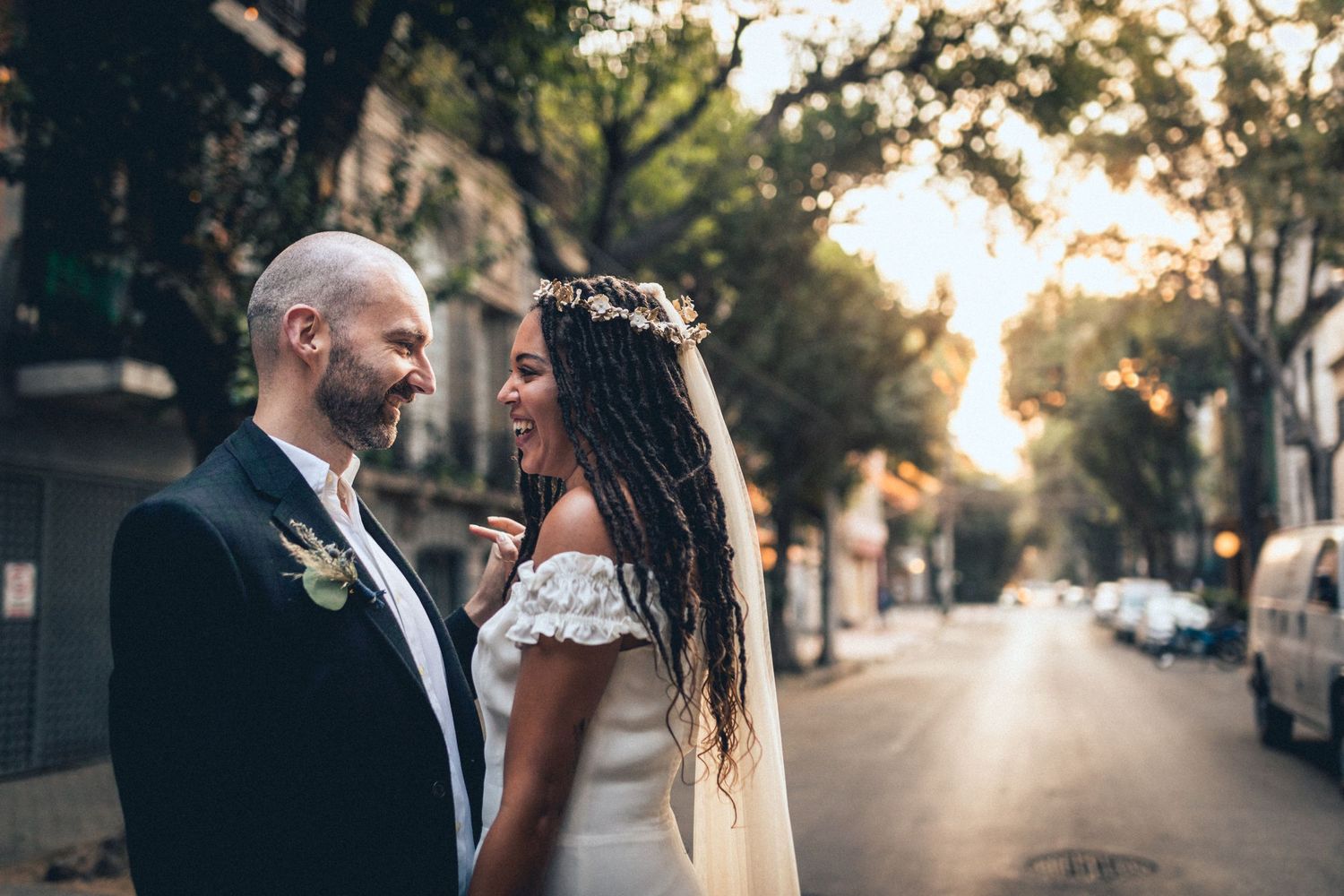 Intimate wedding portrait captured at golden hour on a tree-lined street.