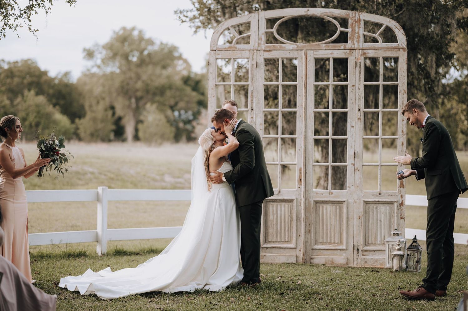 Romantic wedding ceremony at vintage-style gazebo with white decor in outdoor garden setting.