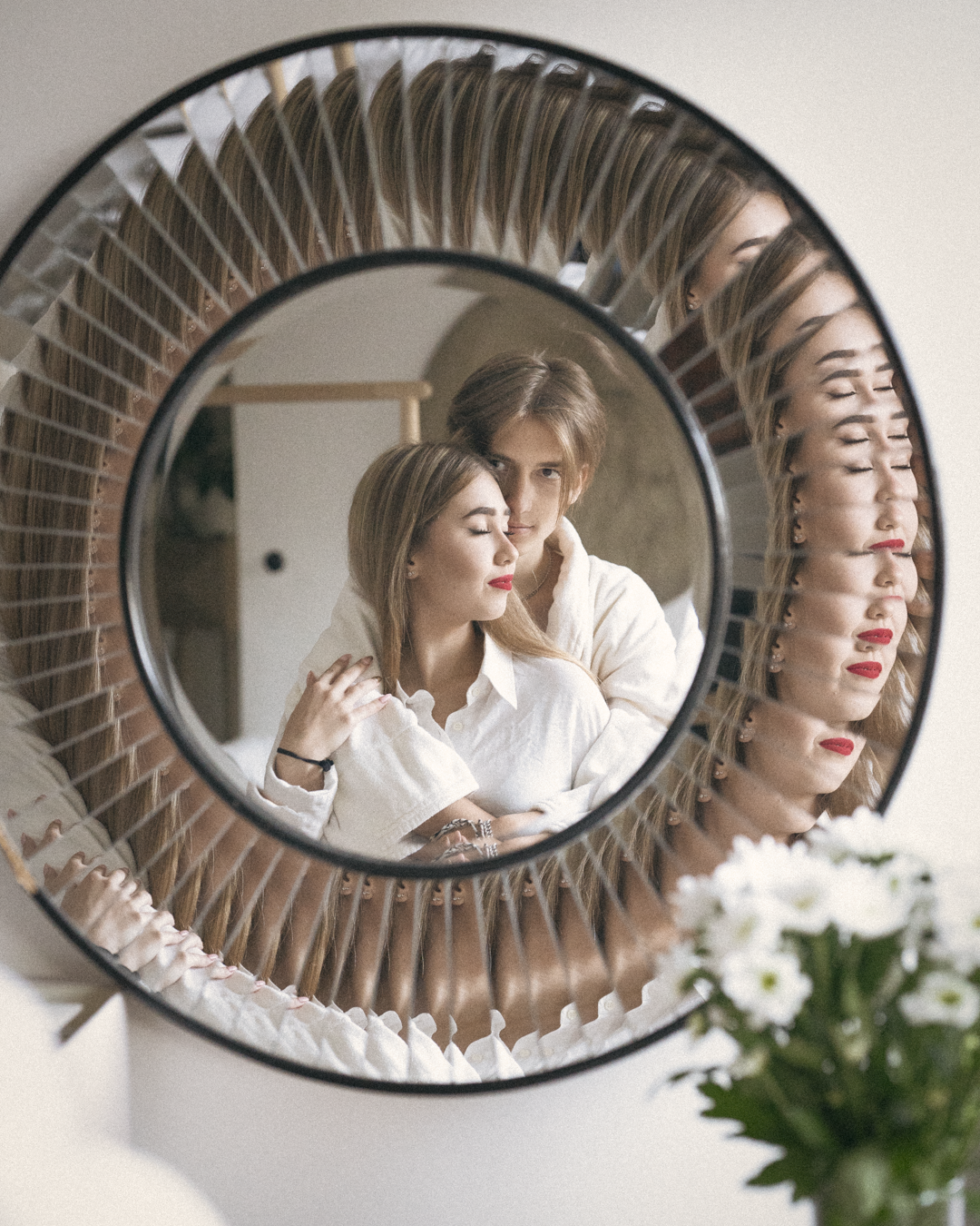 Artistic reflection in decorative circular mirror showing intimate moment.