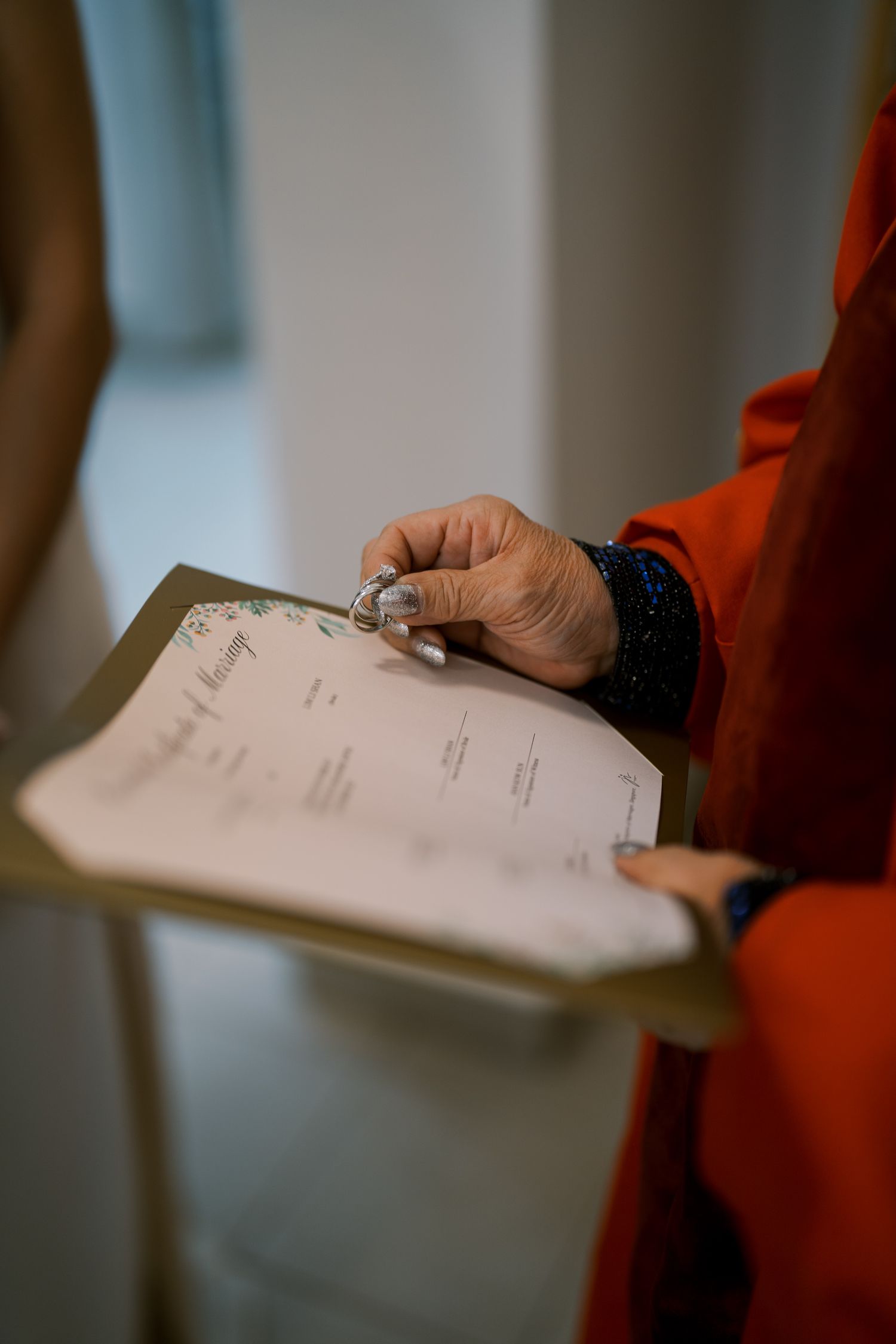 Hands holding a clipboard with paperwork during what appears to be a wedding ceremony.