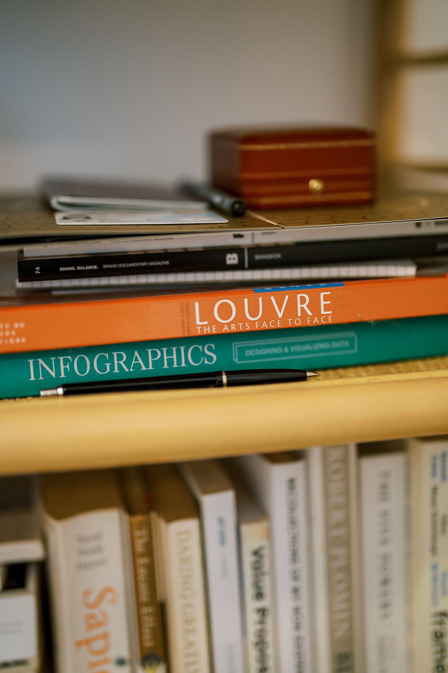 A collection of books on a shelf including titles about the Louvre and infographics.