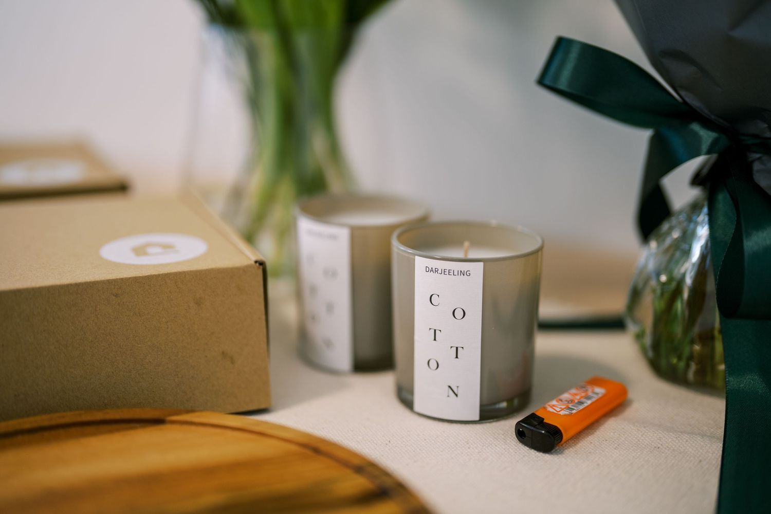 Minimalist interior decor with candles and plants on a wooden surface in natural lighting.